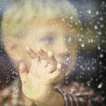 little boy behind the window in the rain - selective focus
