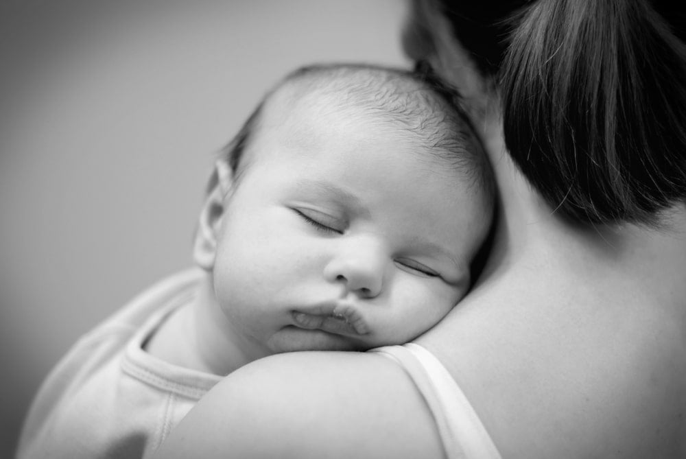 woman with newborn on her shoulder