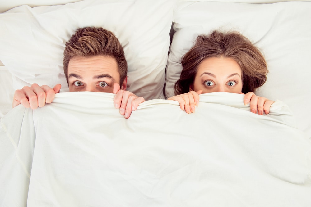 man and woman hiding in bed