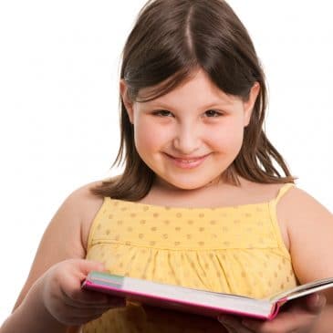 A smiling girl is reading a book; isolated on the white background