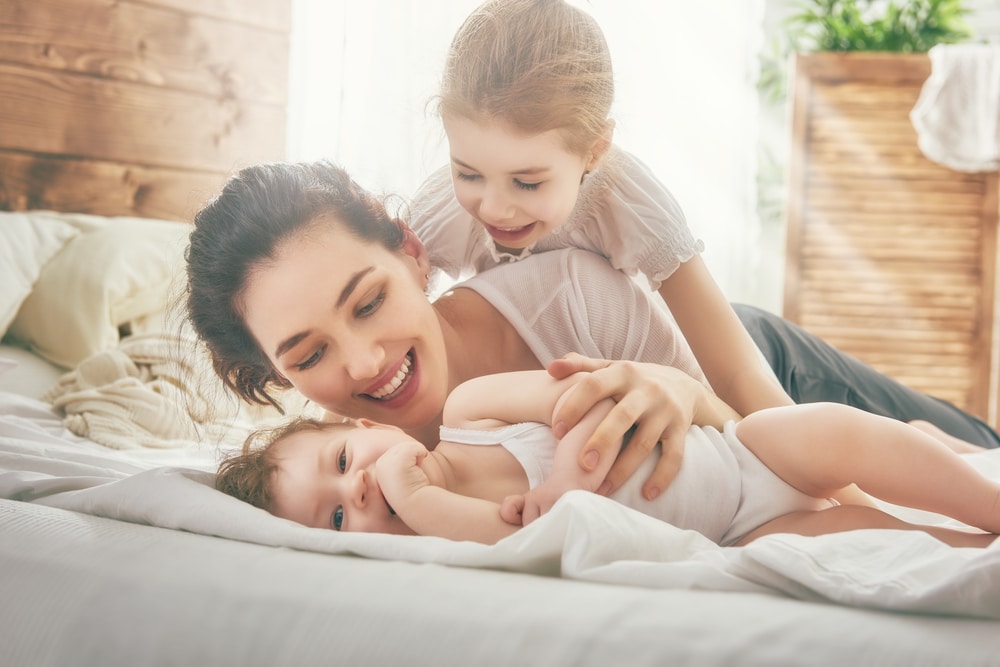 woman happy with kids in bed