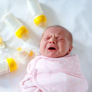 newborn crying with baby bottles