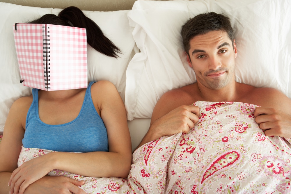 woman sleeping with book in her face with man