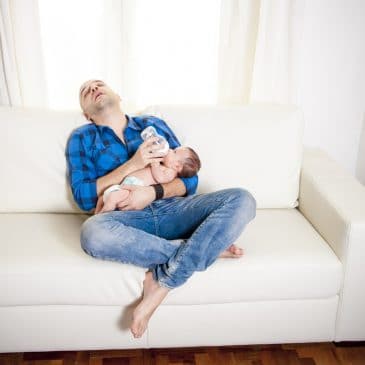 father tired on couch with baby