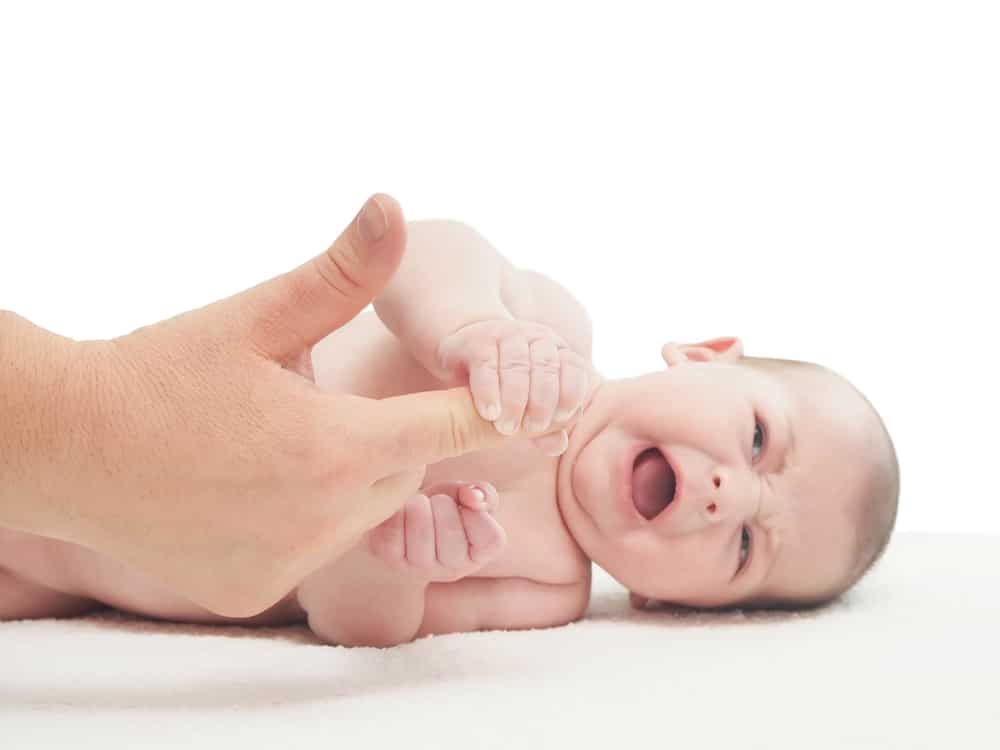 baby crying with adult hand