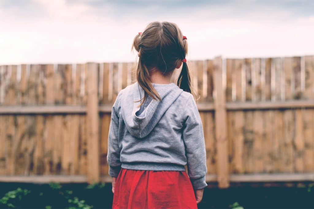 little girl standing in front a fence