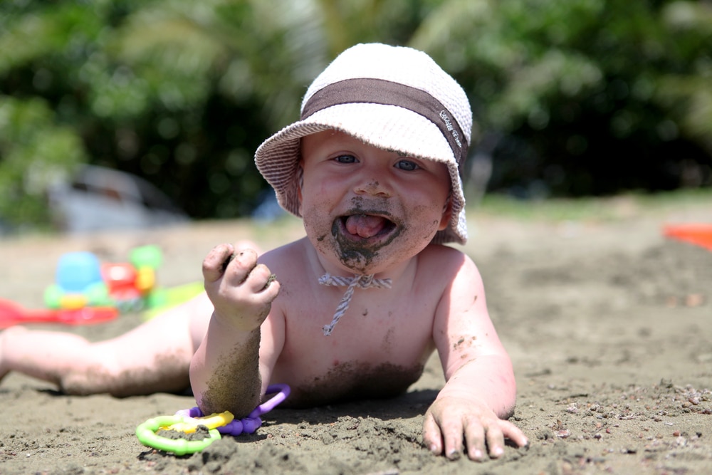 baby eating sand at the beach