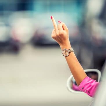 woman showing middle finger in her car