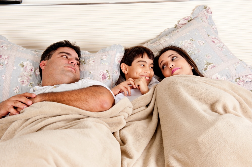 couple in bed with happy kid