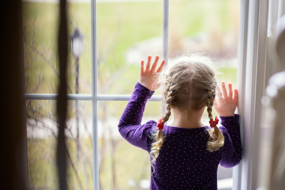 sad little girl watching window