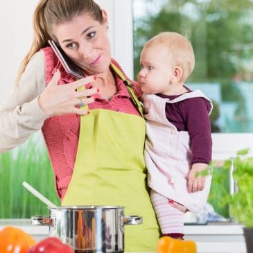 stressed mother cooking with baby and phone