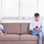 father and kid watching cellphone on couch