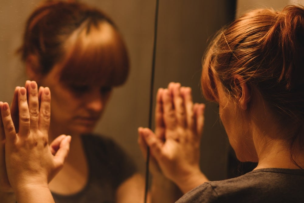 sad woman in front of mirror