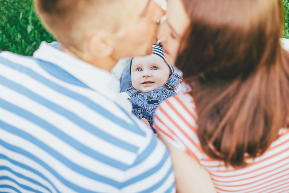 couple kissing with baby