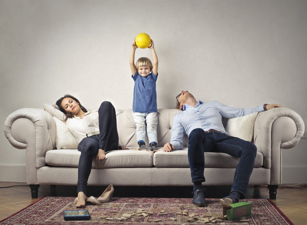 tired parents with kid on couch