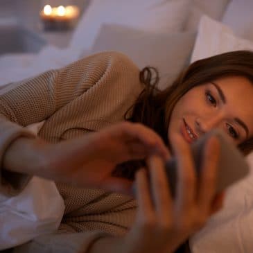 happy woman with cellphone in bed