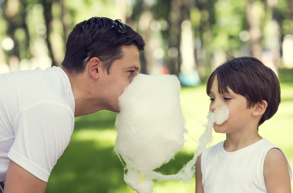 father eating cotton candy with boy