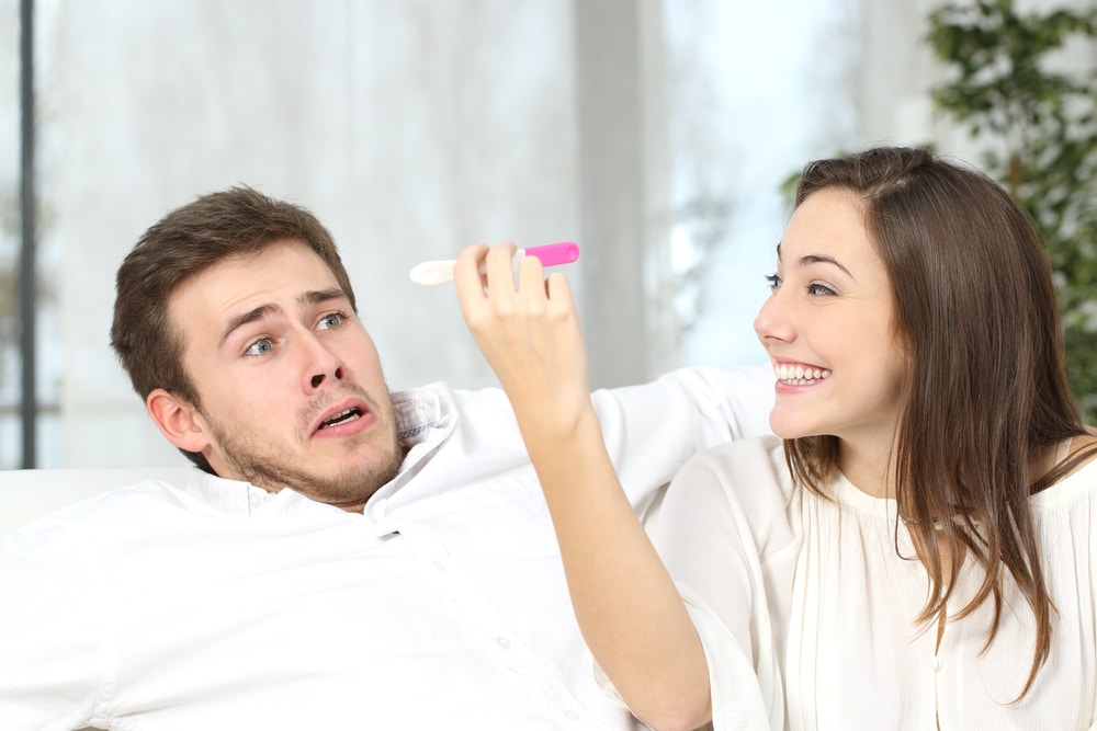 woman holding pregnancy test with scary man
