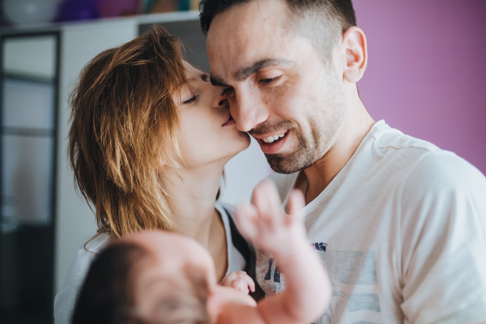 couple kissing with baby