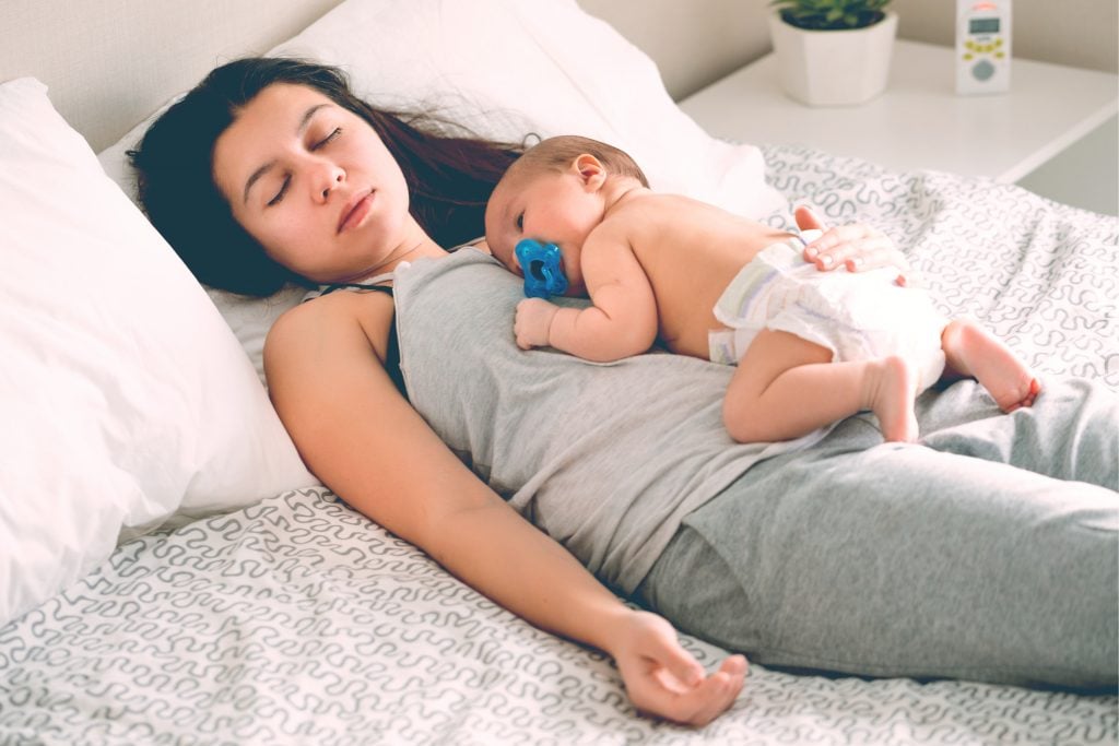 tired mother sleeping with baby