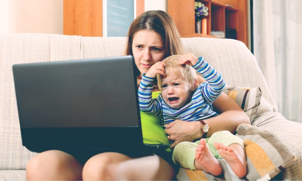 annoyed mother working on computer with kid