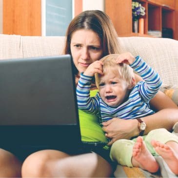 annoyed mother working on computer with kid