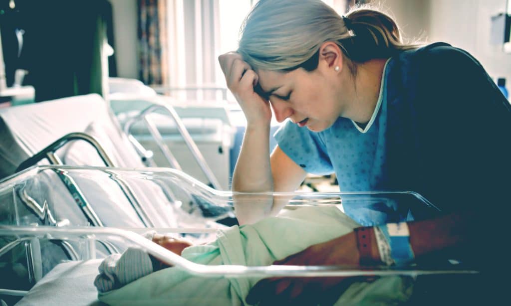 sad new mother with baby a hospital