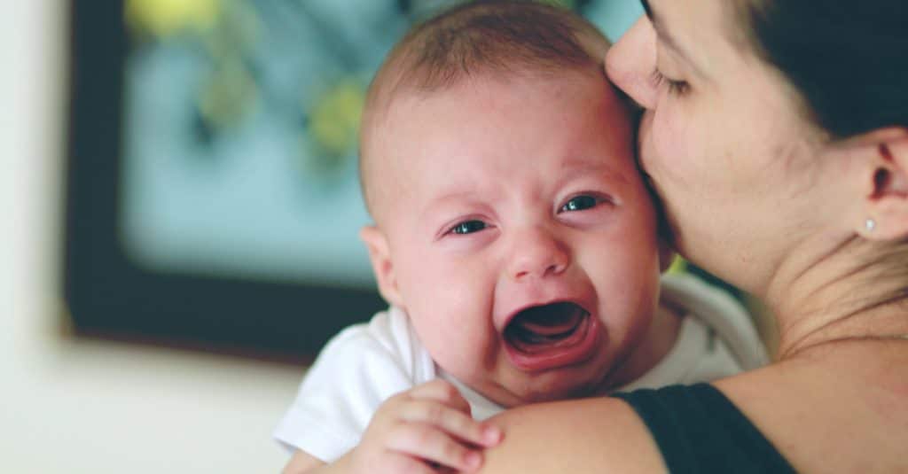 bébé pleure dans les bras de maman