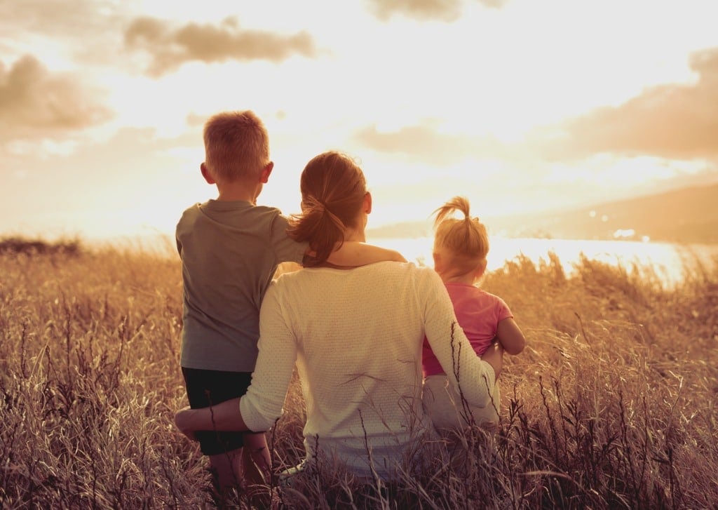 mère avec deux enfants au soleil dans un champ
